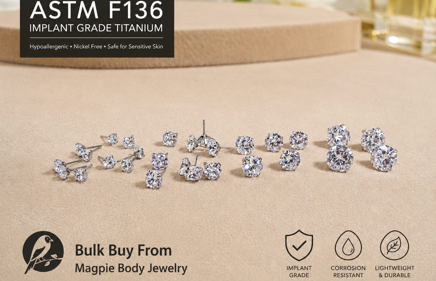 Silver earrings on a beige surface with ASTM F136 implant grade titanium text and Magpie Body Jewelry branding.